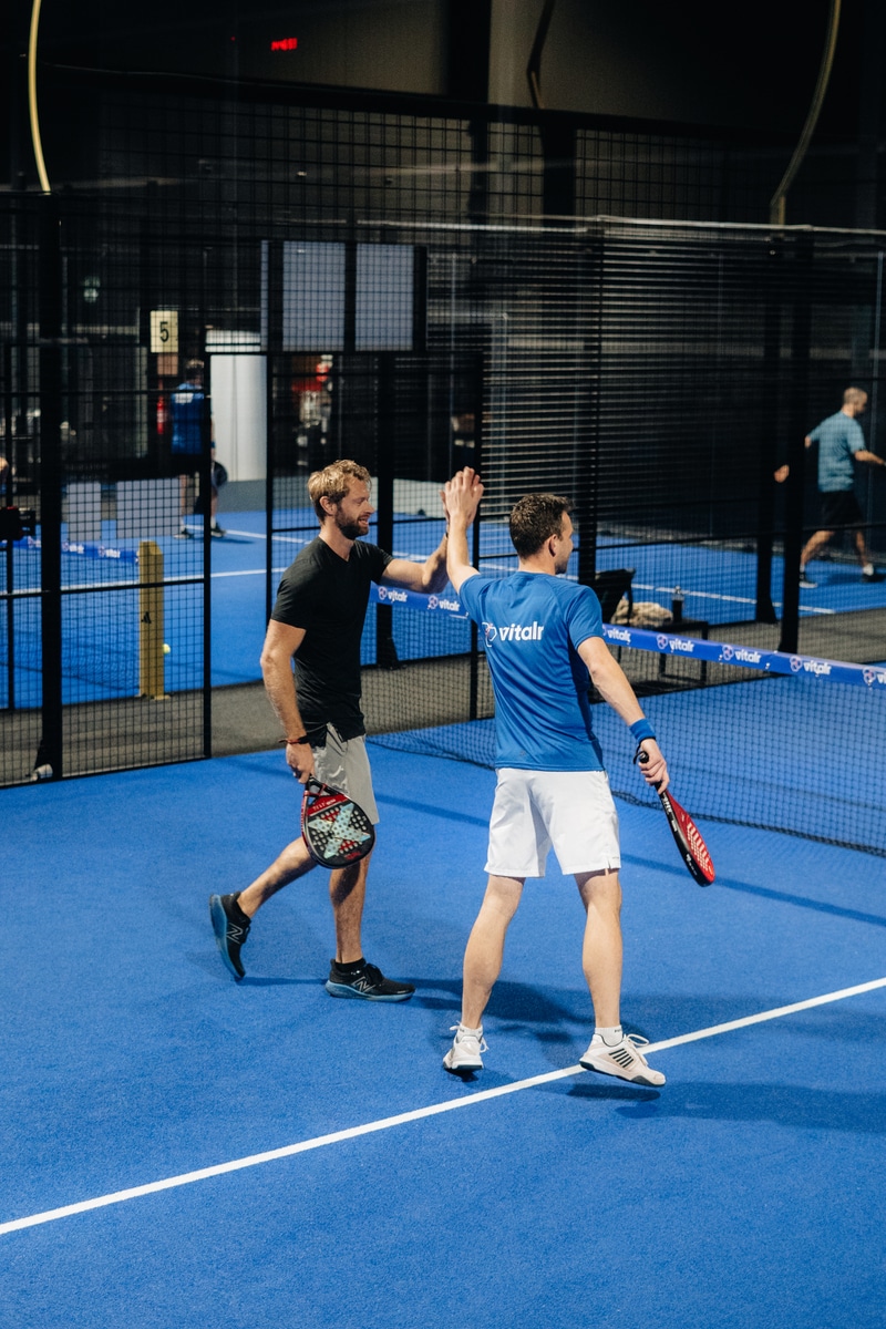 Twee spelers geven elkaar een high five na een punt tijdens de FrontRow Business Padel Cup