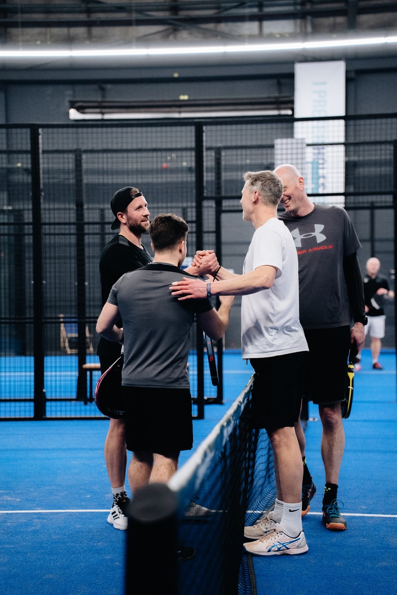 Spelers geven elkaar een hand en feliciteren elkaar na een wedstrijd tijdens de FrontRow Business Padel Cups